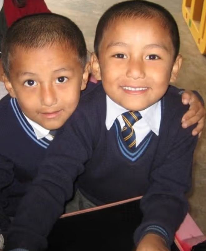 Two young pupils of the Homes in school uniform, arms around each other
